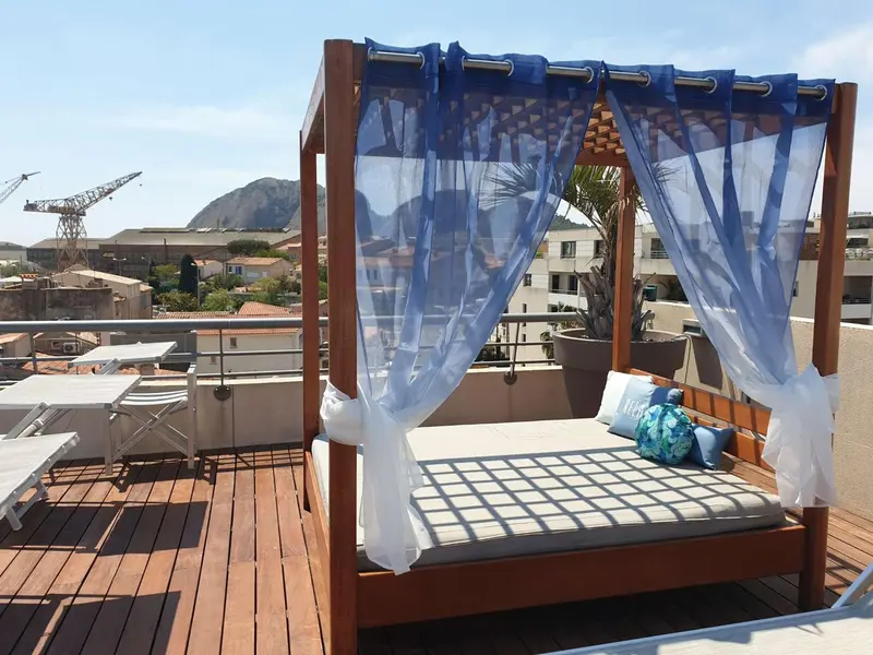 Un espace de détente extérieur avec un lit à baldaquin et une vue sur la ville.