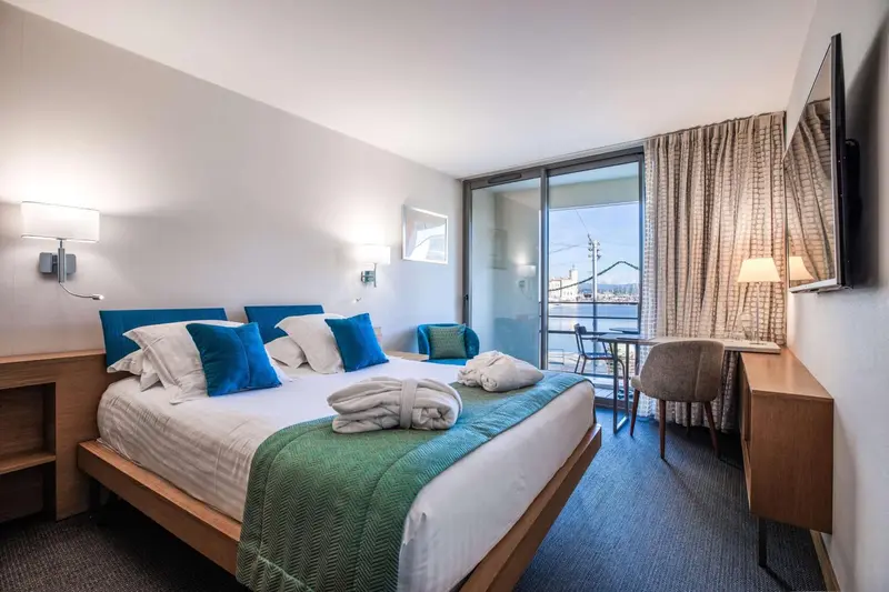 Une chambre lumineuse avec un grand lit et un accès à un balcon.