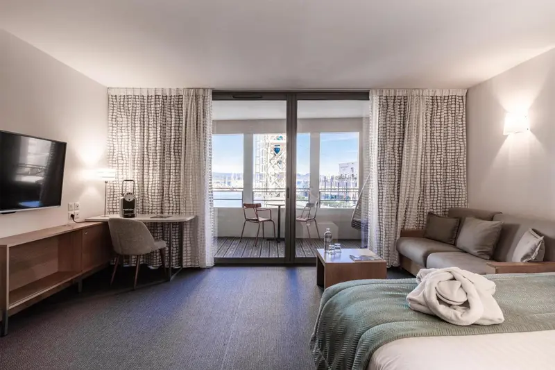 Une chambre lumineuse s'ouvre sur une terrasse avec vue sur la mer.