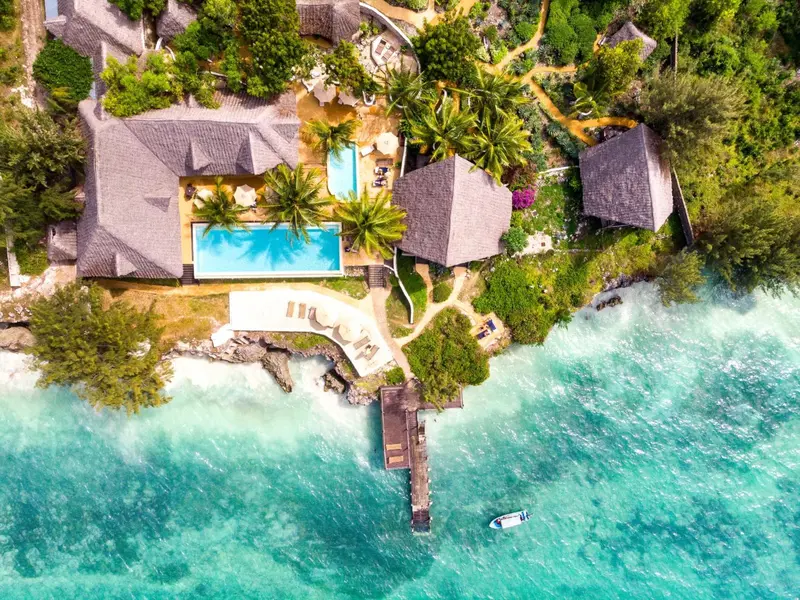 Vue aérienne d'un complexe hôtelier tropical avec piscine et accès à la mer.