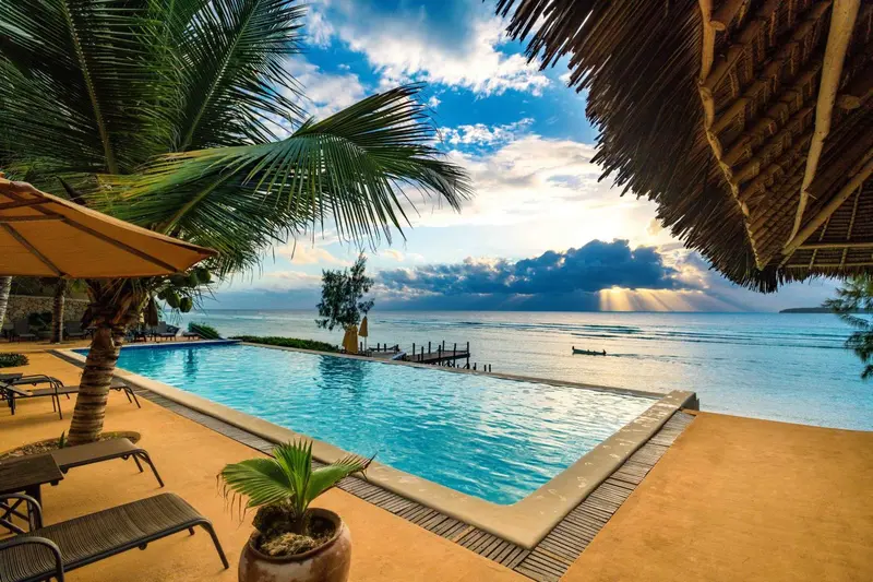 Une piscine à débordement offre une vue sur la mer et le ciel nuageux.