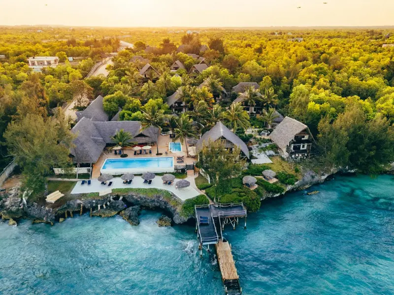 Vue aérienne d'un complexe hôtelier tropical avec piscine et accès à la mer.