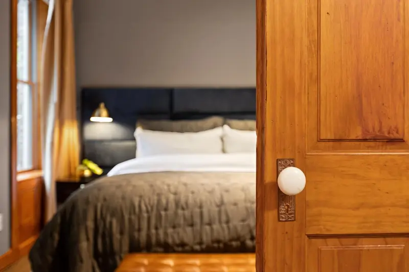 Une chambre avec un grand lit recouvert d'une couverture sombre.