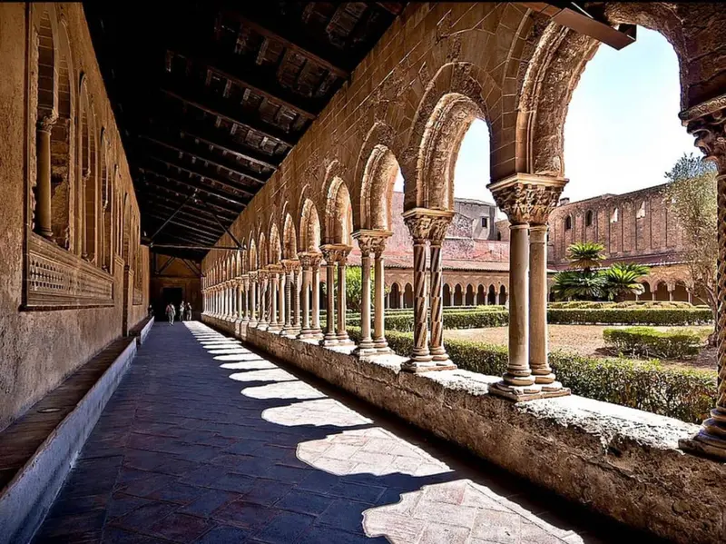 Allée ombragée bordée d'arcades dans un jardin verdoyant.