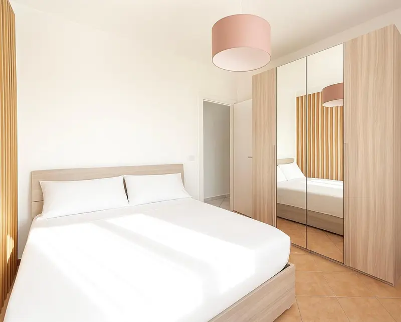 Une chambre lumineuse avec un grand lit et des rangements.