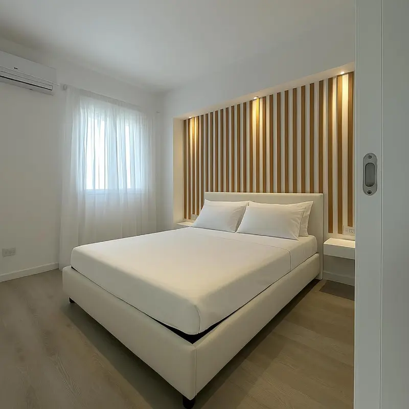 Une chambre lumineuse avec un grand lit recouvert de blanc.