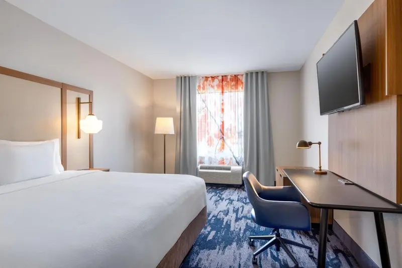 Une chambre d'hôtel lumineuse avec un lit, un bureau et une télévision.