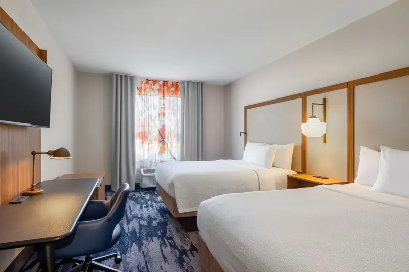 Une chambre d'hôtel avec deux lits simples et un bureau.