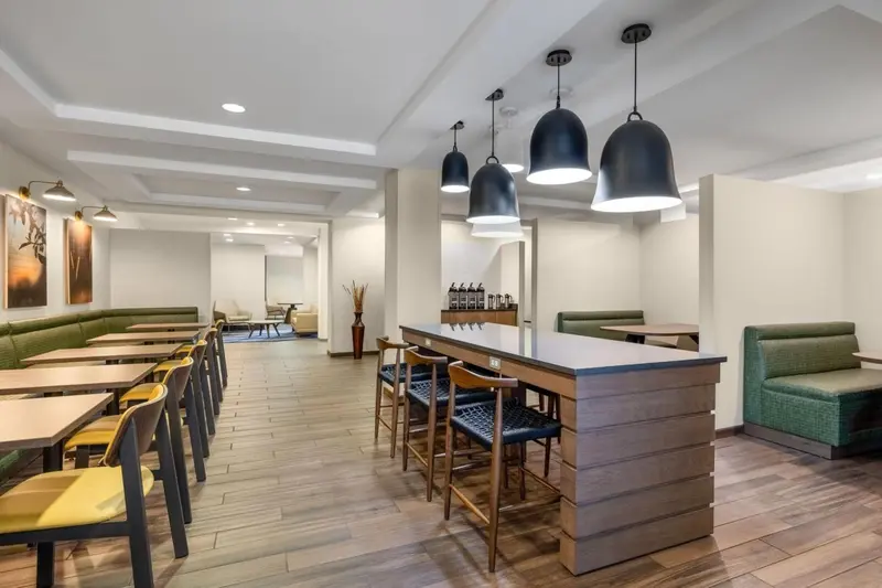 Une salle lumineuse avec des tables, des chaises et un comptoir de bar.