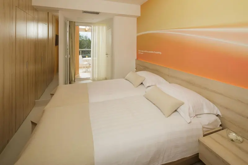 Une chambre lumineuse avec un grand lit et un accès à un balcon.