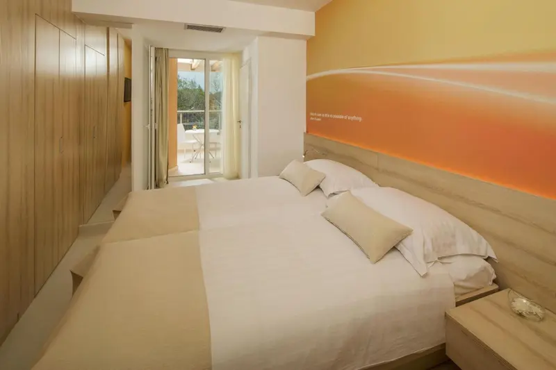 Une chambre lumineuse avec un grand lit et un accès à une terrasse.
