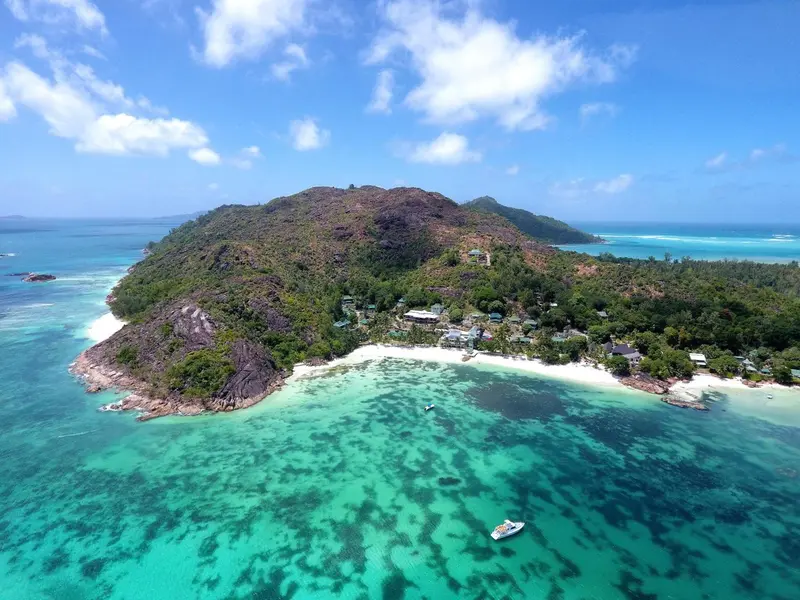 Vue aérienne d'une île tropicale avec une plage de sable blanc et une végétation luxuriante.