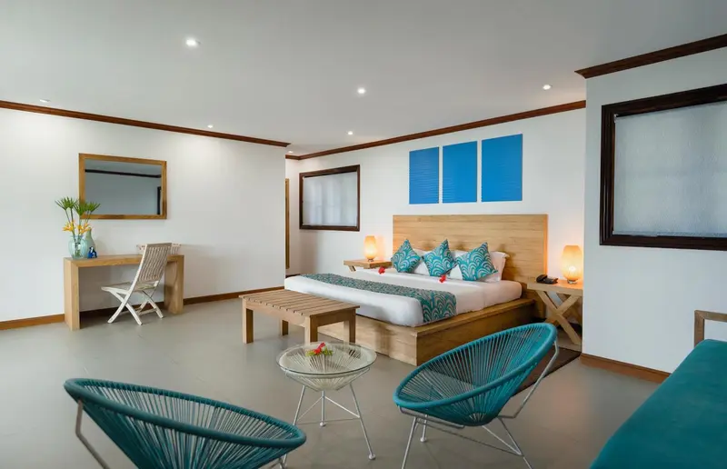 Une chambre lumineuse avec un grand lit et un coin salon.