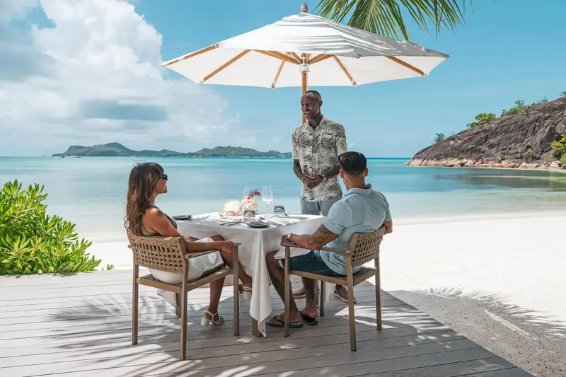 Un couple déguste un repas en plein air face à la mer.
