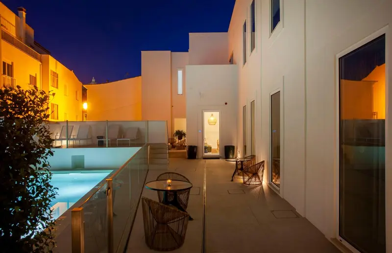 Une cour intérieure lumineuse avec une piscine et des tables basses.