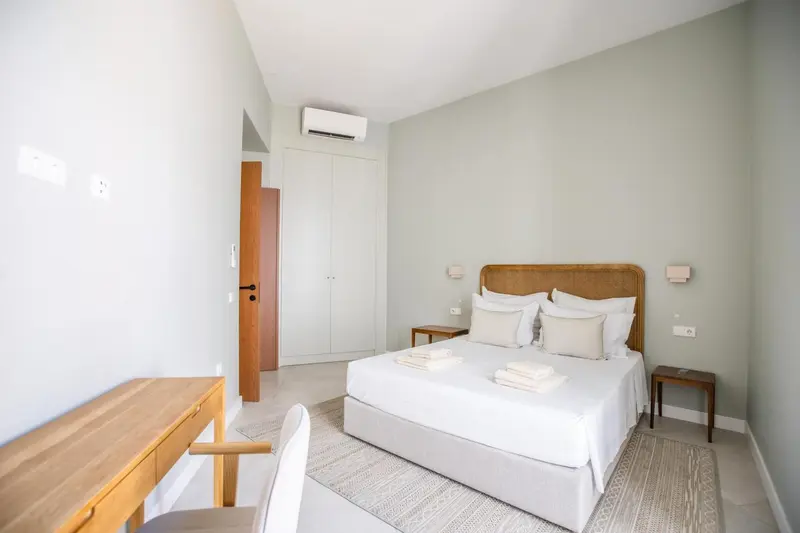 Une chambre lumineuse avec un lit double et un bureau en bois.