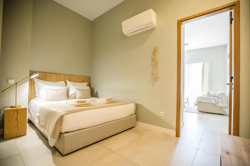 Une chambre lumineuse avec un grand lit et un accès à un autre espace.