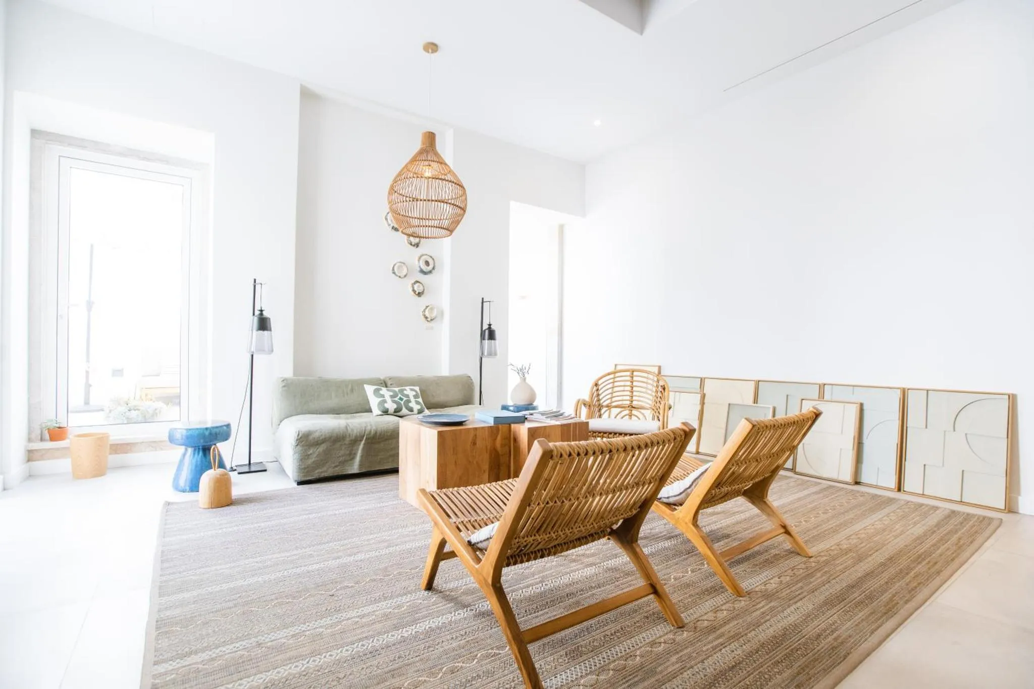 Espace de détente lumineux avec canapés et fauteuils en rotin.