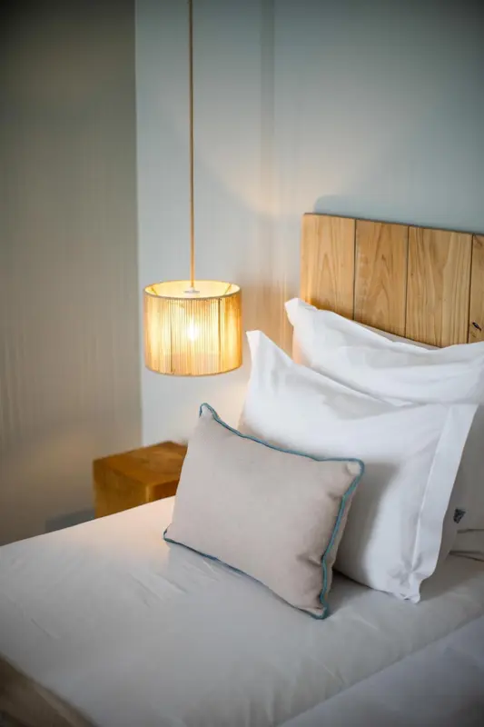 Un lit avec des oreillers blancs et une lampe suspendue.