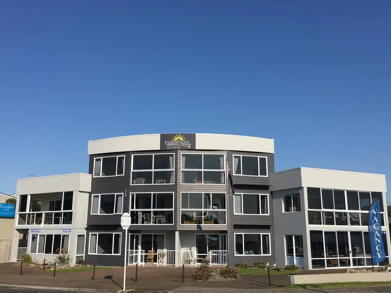 Bâtiment moderne à deux étages avec une façade grise et blanche, situé en bord de mer.