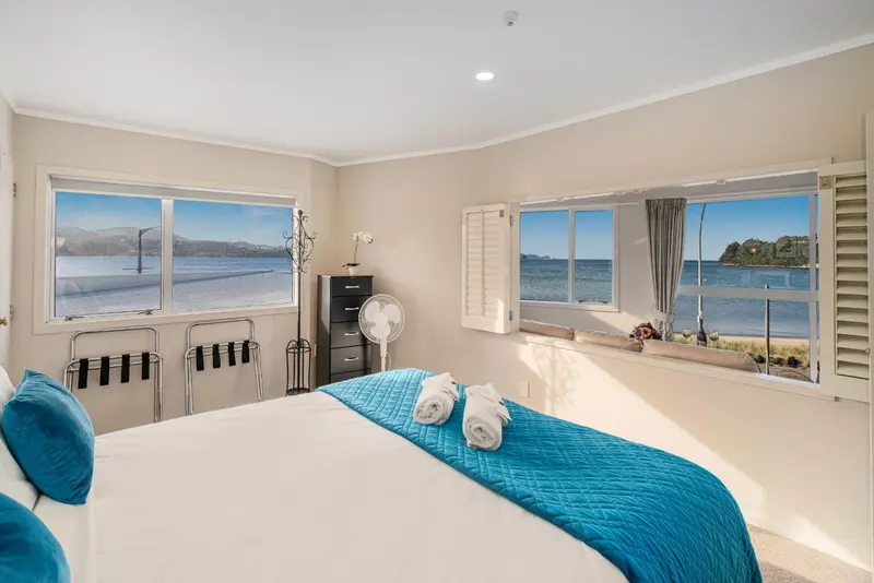 Une chambre lumineuse avec un grand lit donnant sur une vue mer.