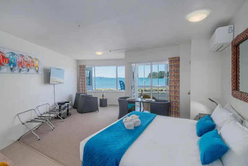 Chambre lumineuse avec un grand lit et vue sur la mer.