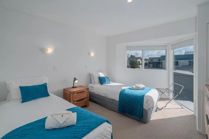 Chambre lumineuse avec deux lits simples et une vue sur l'extérieur.