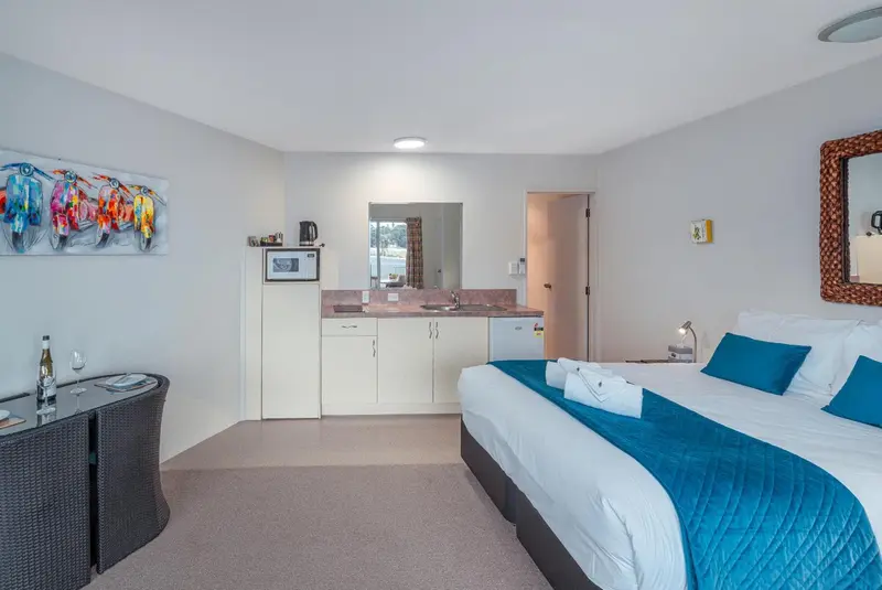 Une chambre lumineuse avec un lit fait et un coin cuisine.