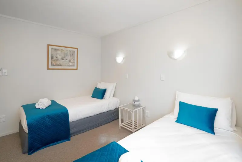 Une chambre lumineuse avec deux lits simples et une décoration sobre.