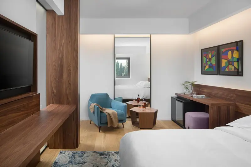 Une chambre d'hôtel moderne avec un lit, un fauteuil et un bureau.