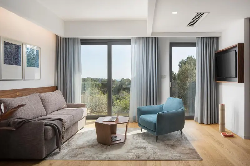Un salon lumineux avec canapés et fauteuils face à de grandes baies vitrées.