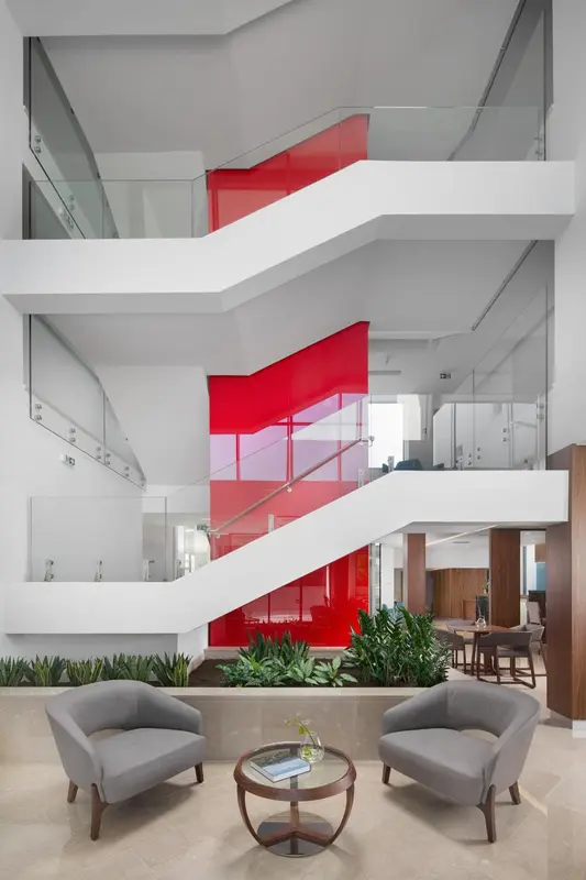 Un espace intérieur moderne avec un escalier rouge et des fauteuils.