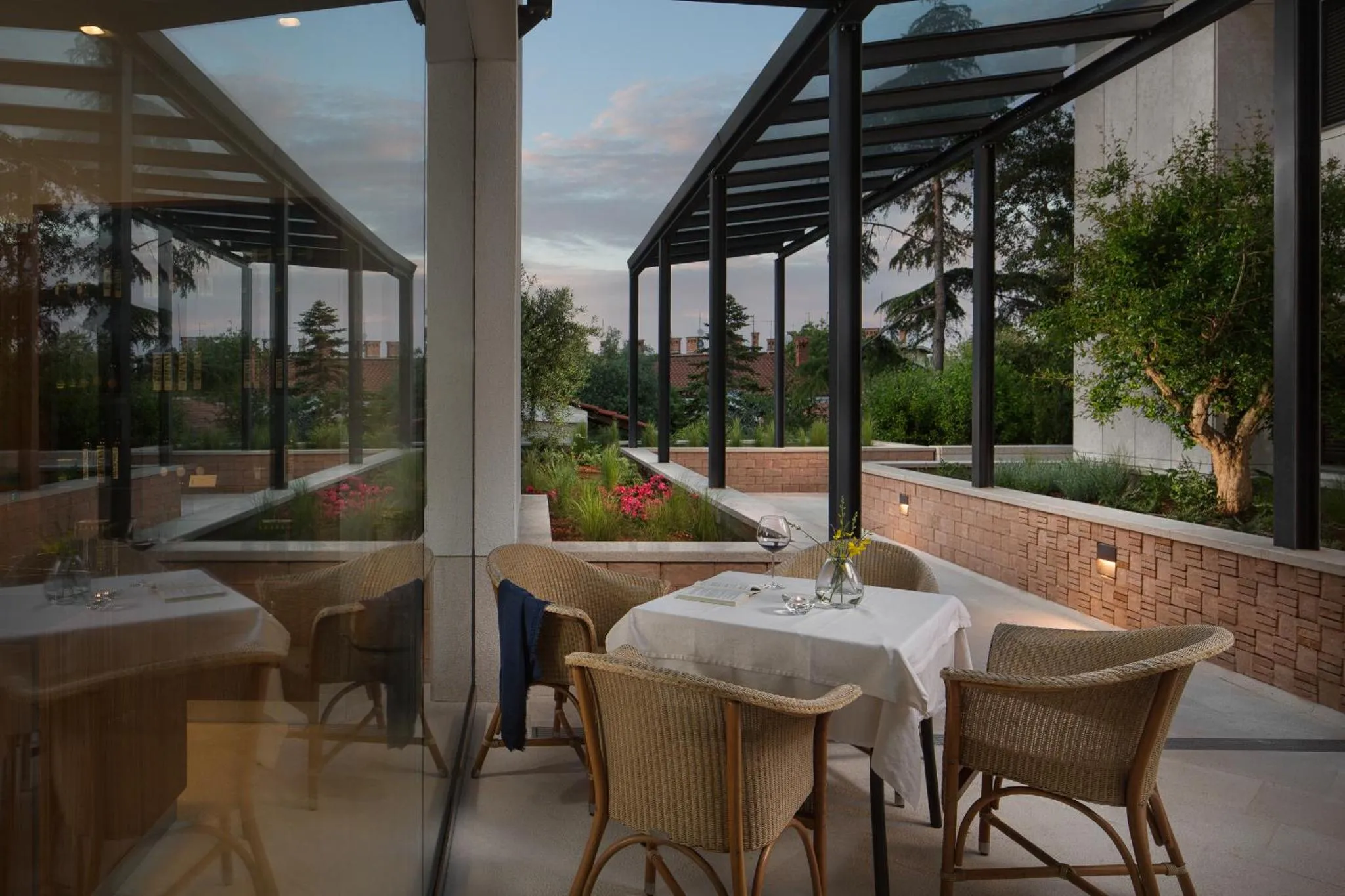 Tables dressées sur une terrasse ombragée avec vue sur un jardin.
