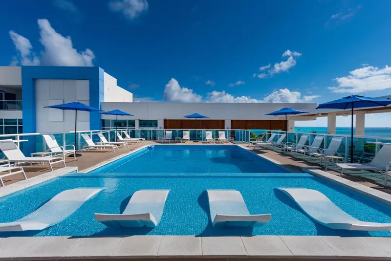 Terrasse avec piscine et chaises longues ensoleillées.