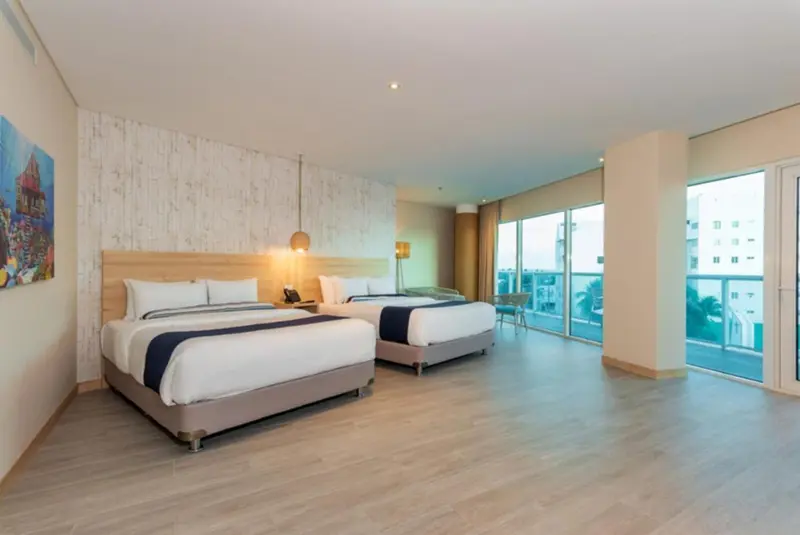 Une chambre lumineuse avec deux lits et une vue sur la mer.