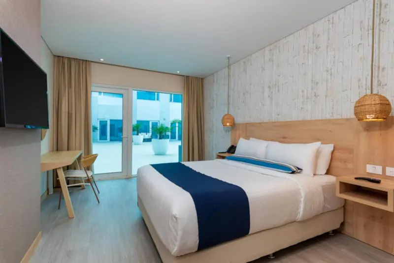 Une chambre lumineuse avec un grand lit et un accès à une terrasse.