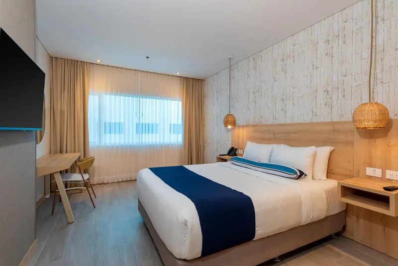 Chambre lumineuse avec un grand lit et une fenêtre.