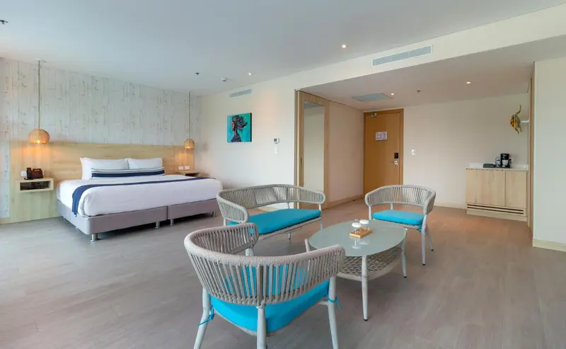 Une chambre lumineuse avec un lit double et un coin salon.