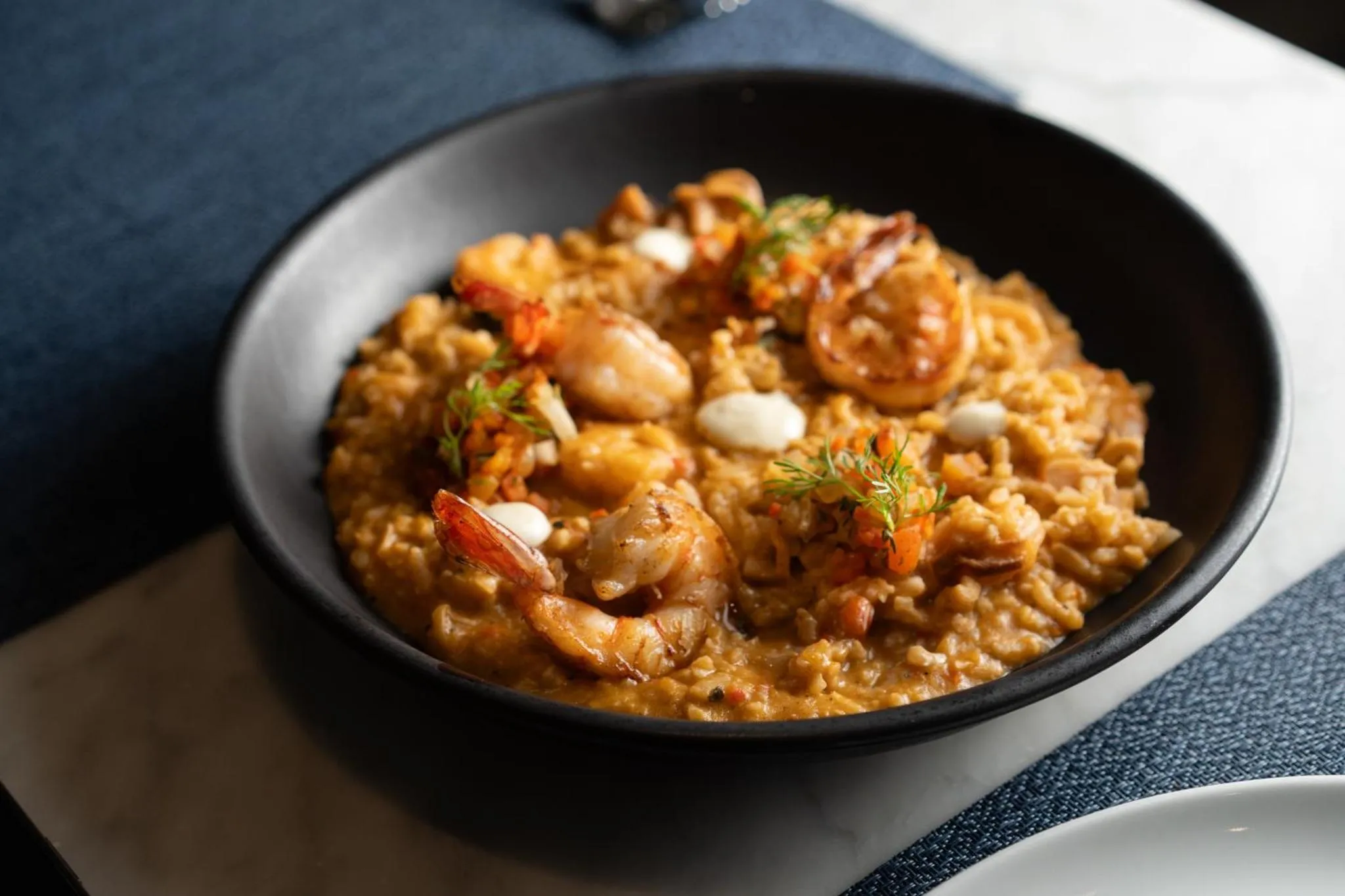 Un plat de riz aux crevettes est présenté dans un bol noir.