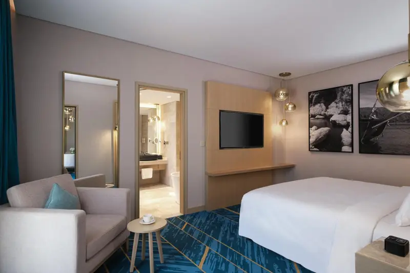 Une chambre lumineuse avec un lit double et un coin salon.