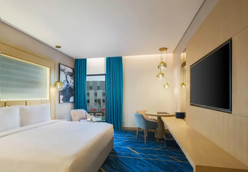 Chambre lumineuse avec un lit double et un espace repas.