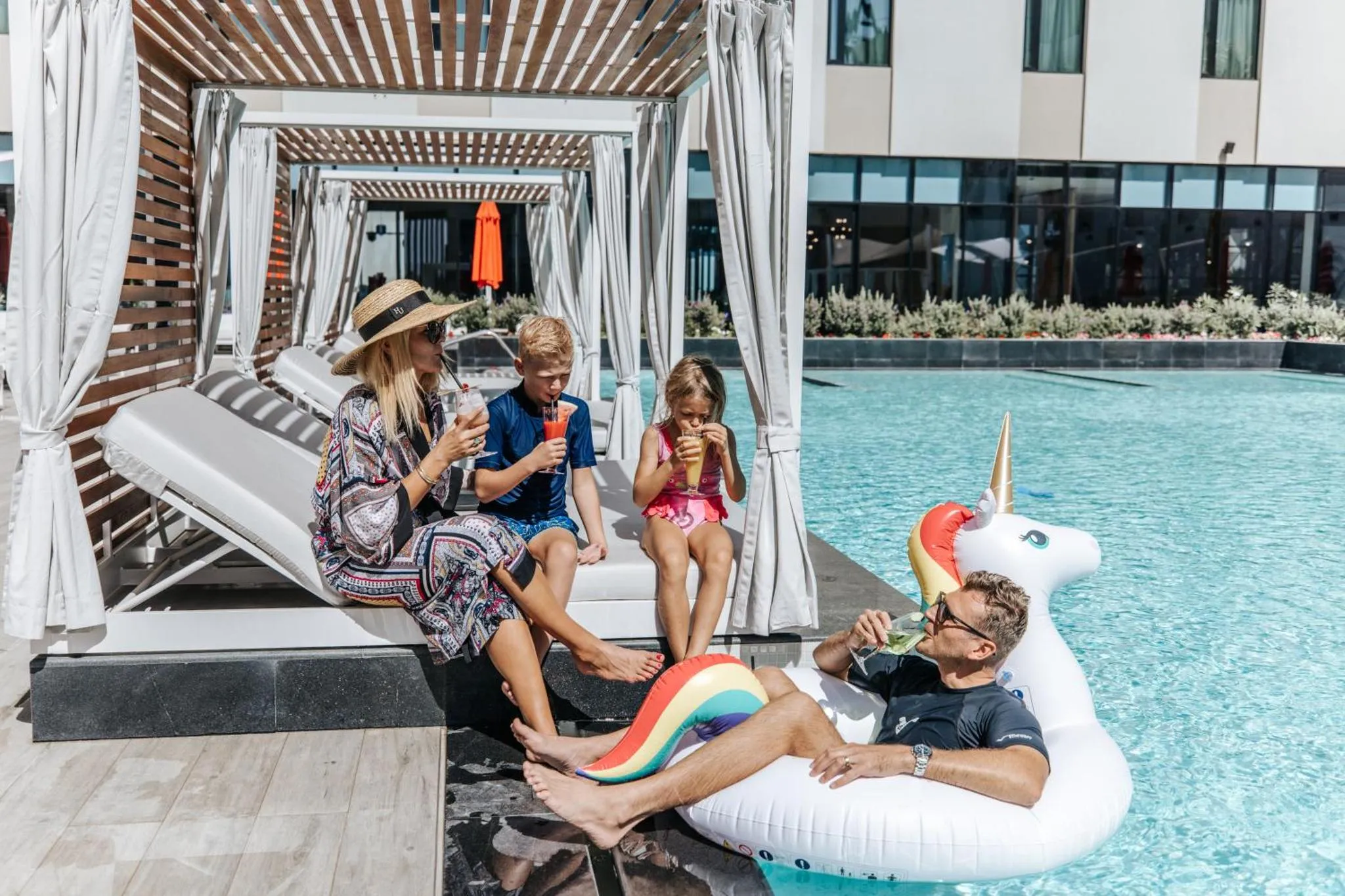 Une famille se détend au bord d'une piscine ensoleillée.