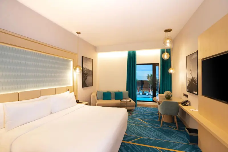 Chambre lumineuse avec un grand lit et un coin salon.