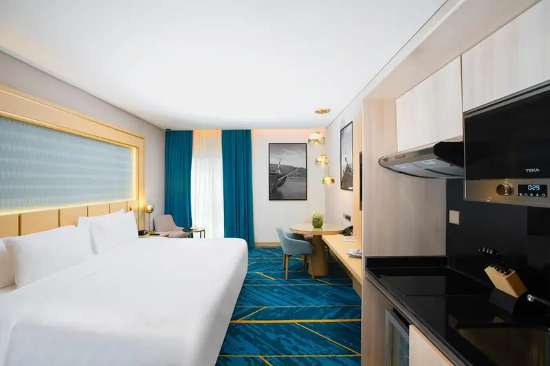 Chambre lumineuse avec un grand lit et un coin cuisine.