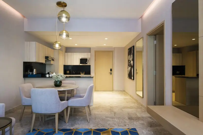 Une salle à manger lumineuse avec une kitchenette en fond.
