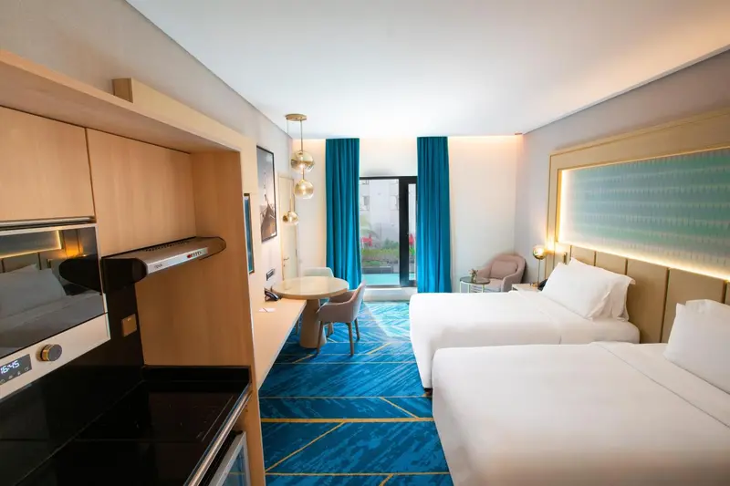 Chambre lumineuse avec deux lits simples et un espace repas.