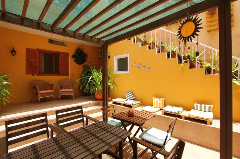 Terrasse ombragée avec mobilier de jardin et plantes en pots.