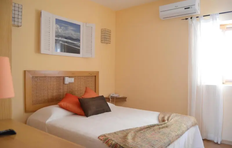 Une chambre lumineuse avec un lit recouvert d'une couverture colorée.
