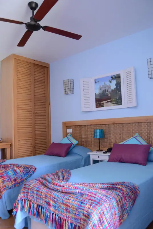 Chambre lumineuse avec deux lits simples et une décoration colorée.