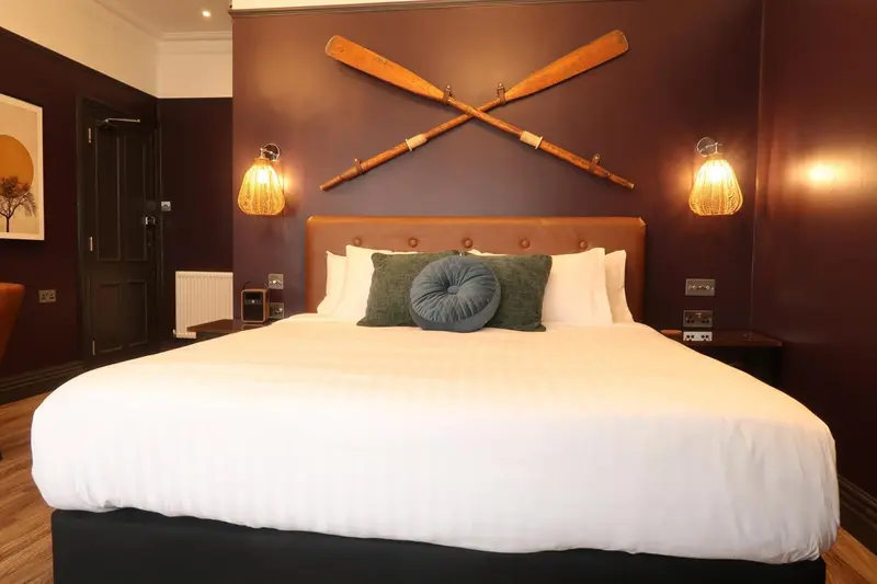 Une chambre avec un grand lit recouvert de linge blanc et décorée de rames.